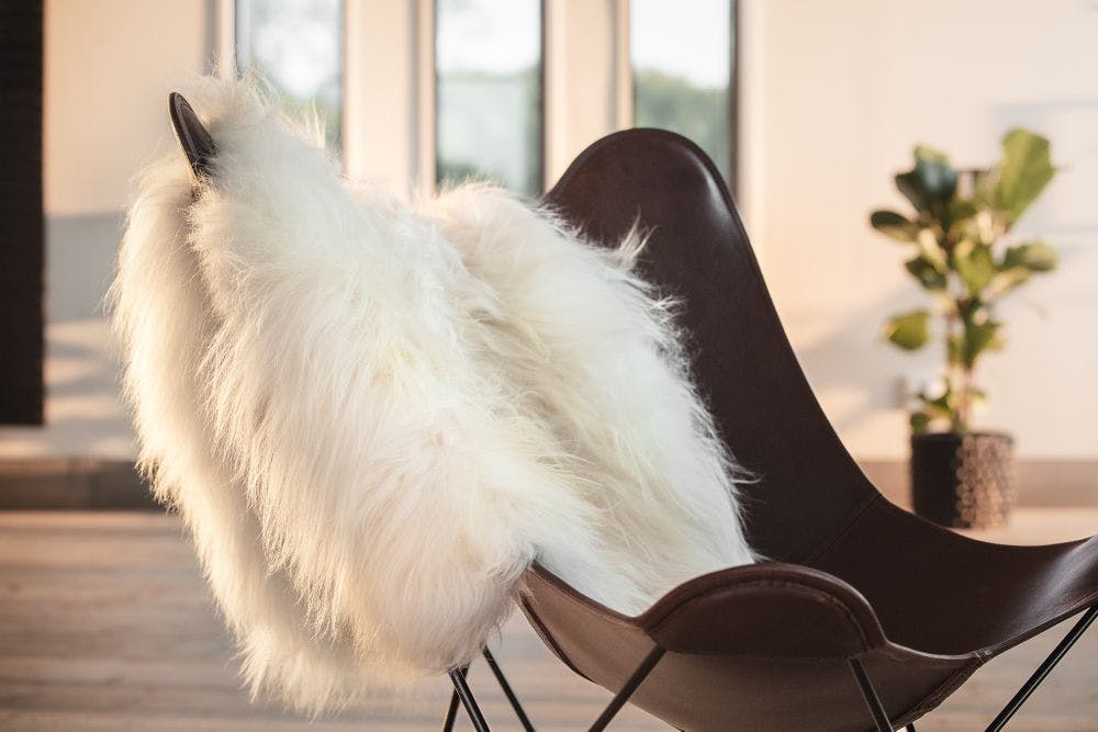 brown leather butterfly chair with white sheepskin rug