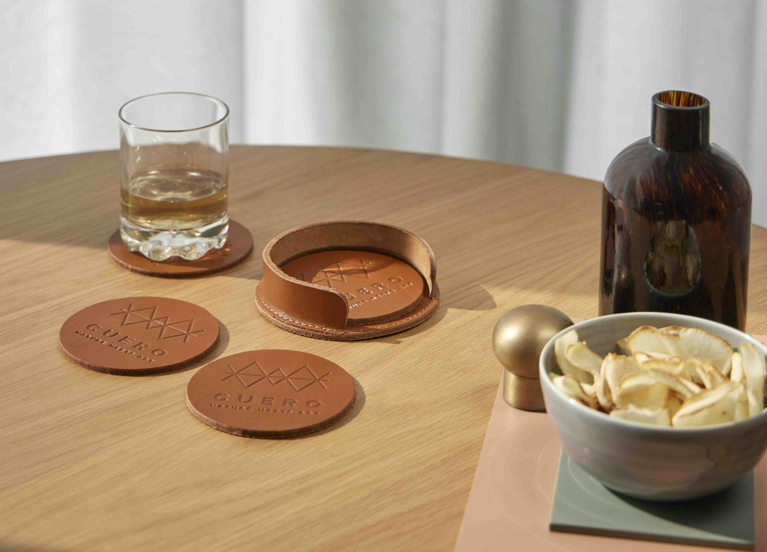 leather coasters with drink on wooden table