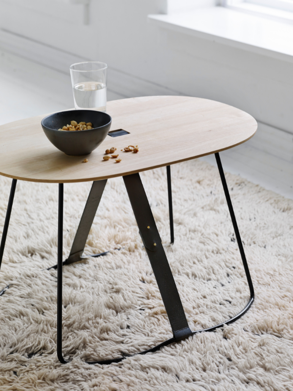 birchwood, steel and leather side table with peanuts and glass of water on rug